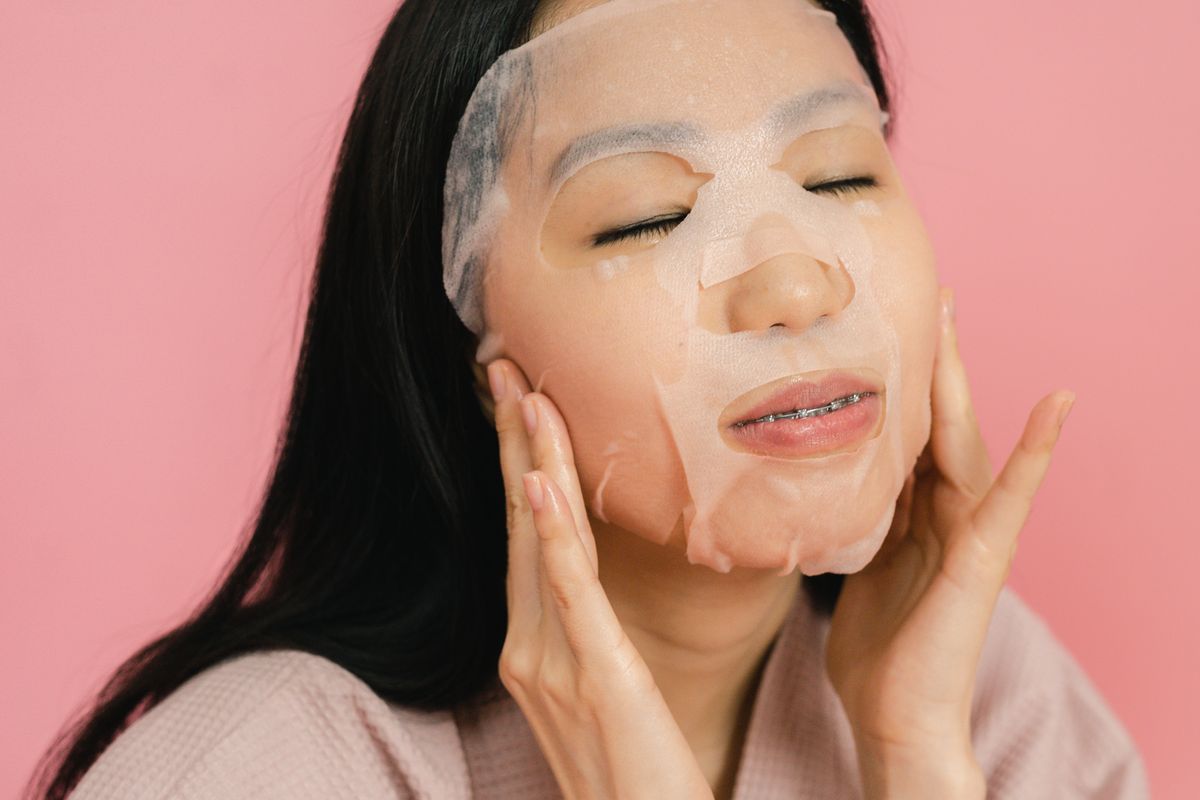 Asian woman applying Korean sheet mask